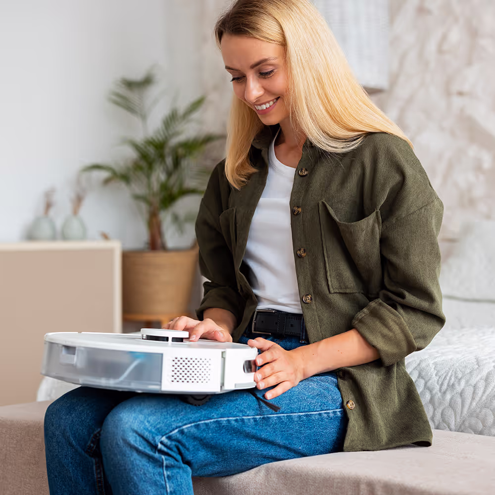 Mujer feliz en el sofá disfrutando de su tiempo libre con el robot aspirador Essentio